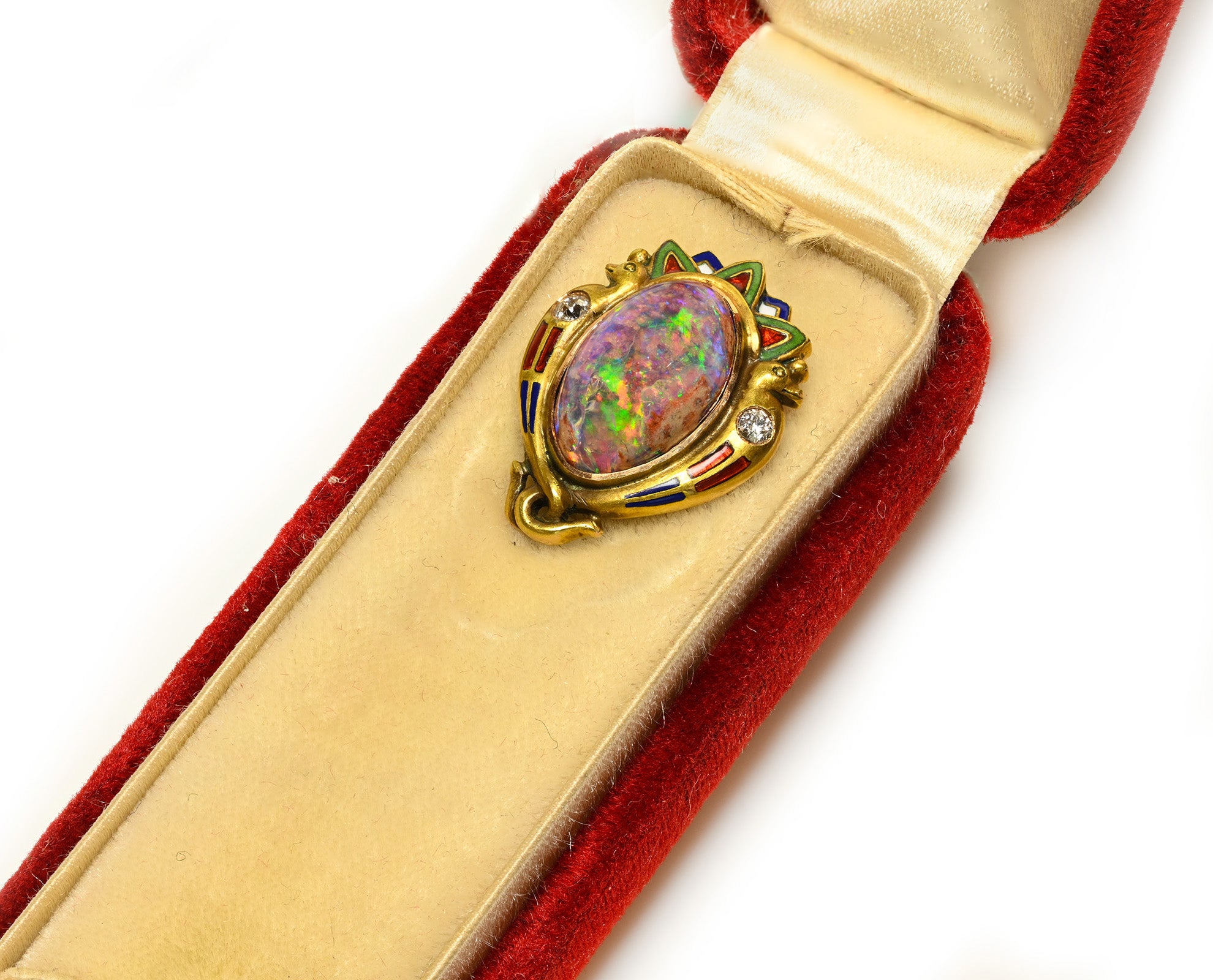Antique gold brooch featuring an oval opal gemstone with vibrant multicolor play-of-color, set in a decorative gold frame with small colored enamel accents, displayed inside an open red velvet jewelry box.