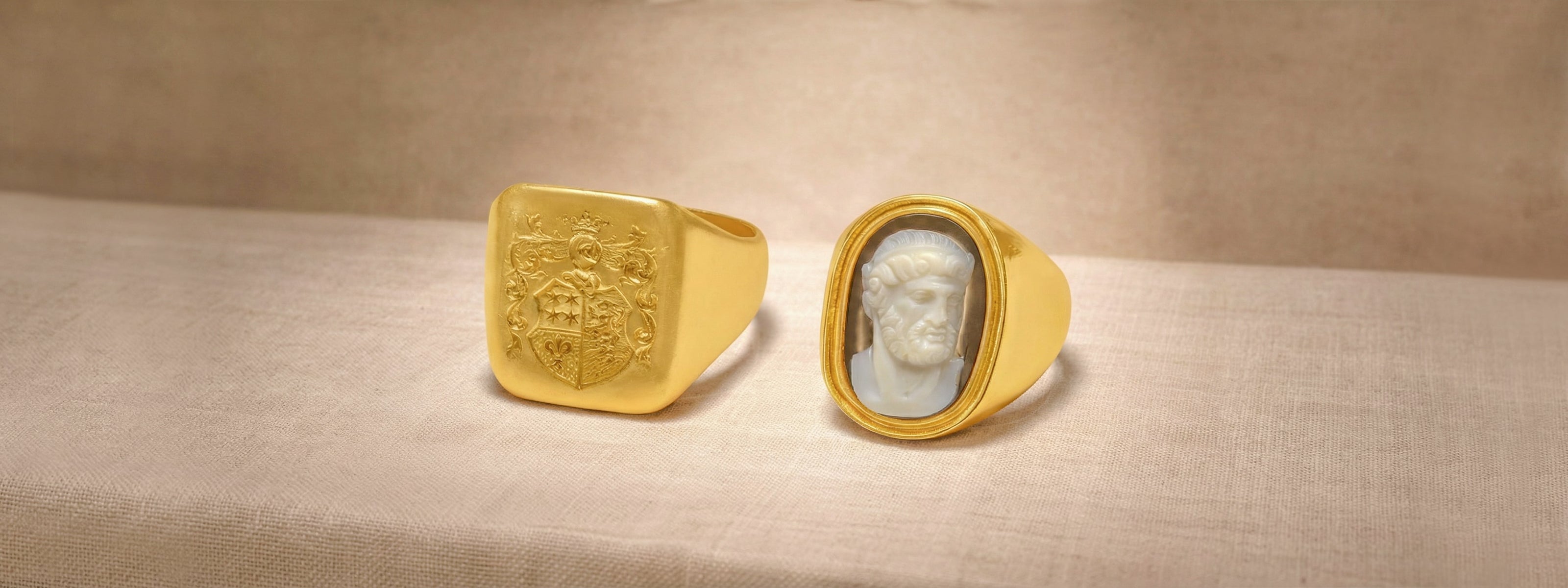 Two antique signet and cameo rare gold rings with engraved designs on a beige surface