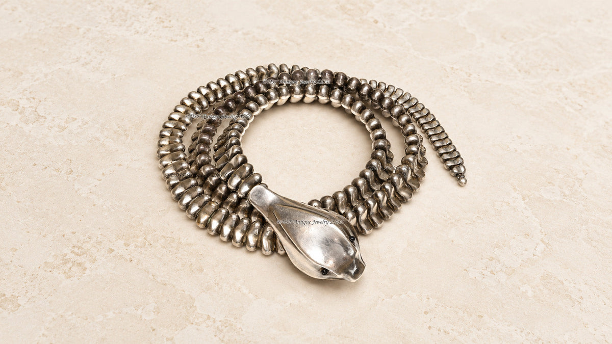 Alt text for the stone-background image: Vintage Elsa Peretti silver snake belt necklace displayed on a warm stone background.
