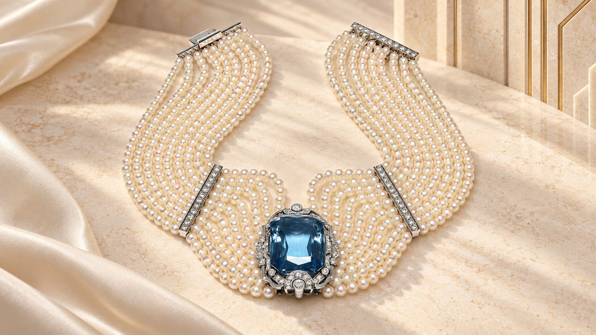 Art Deco aquamarine, pearl and diamond platinum necklace on an marble editorial background.”